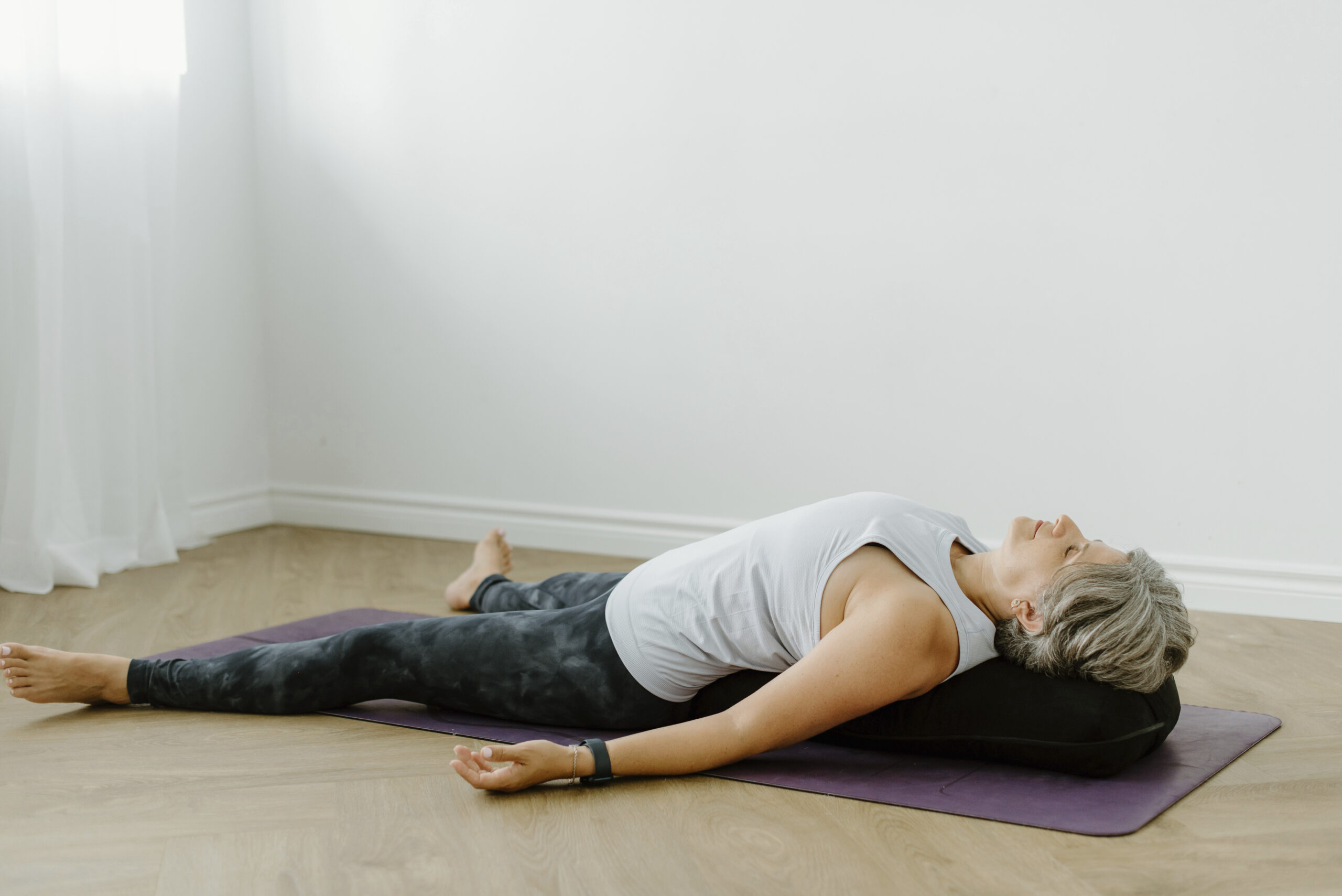 Woman lying on yoga mat at home Woman relaxing in a yoga pose on a mat indoors